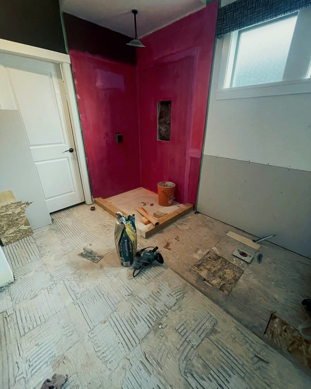 The shower under construction, walls coated in waterproofing membrane over a formed mortar pan and curb.