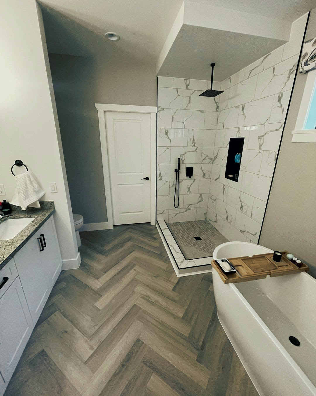 The finished ensuite with a freestanding tub, walk-in shower and herringbone floor.