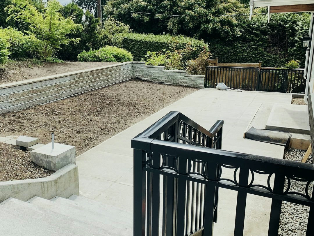 The finished terrace: stepped retaining walls wrapping the garden, a bed graded ready for planting, and the patio and railings in place.