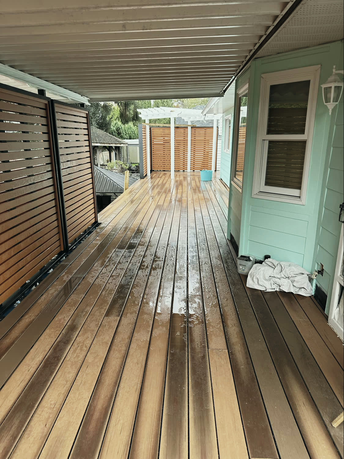 The sheltered lower walkway, with hardwood decking running between the house and a slatted screen.