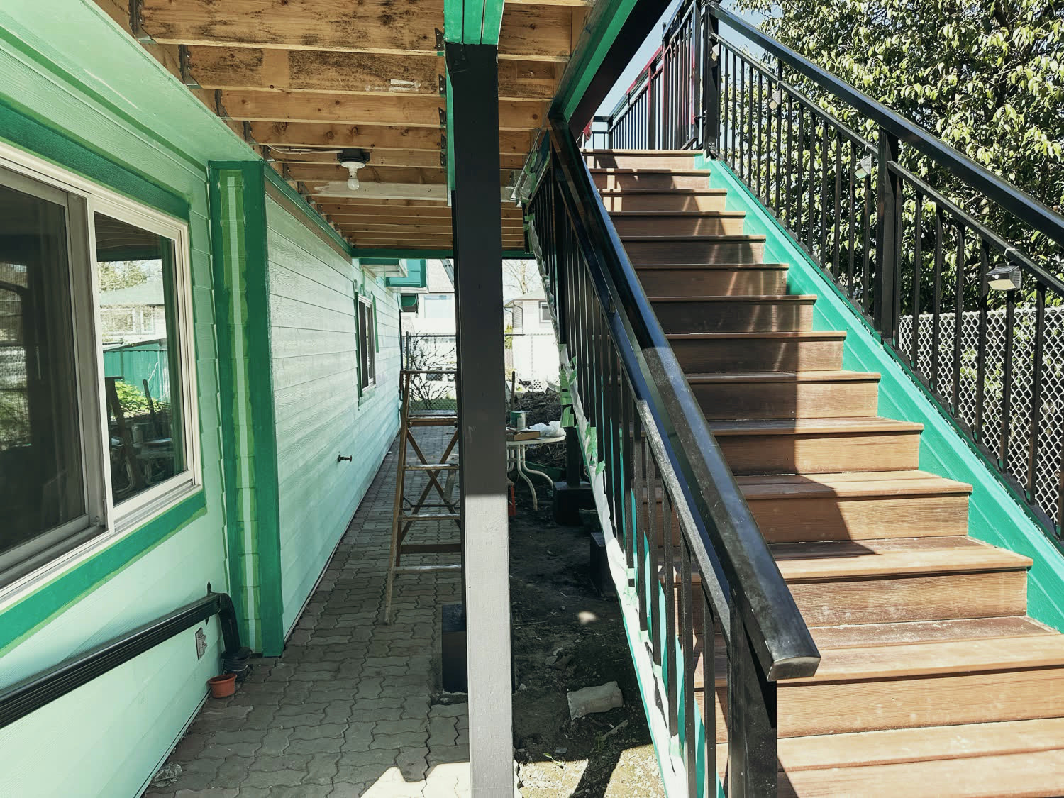 New hardwood stair treads with black railings running down the side of the repainted house.