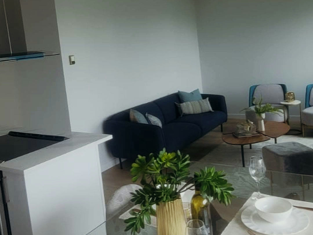 The finished living and dining area, staged for viewing, with the kitchen open beyond it.